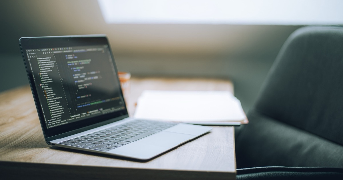 Open laptop displaying code on a desk in a bright, modern workspace.
